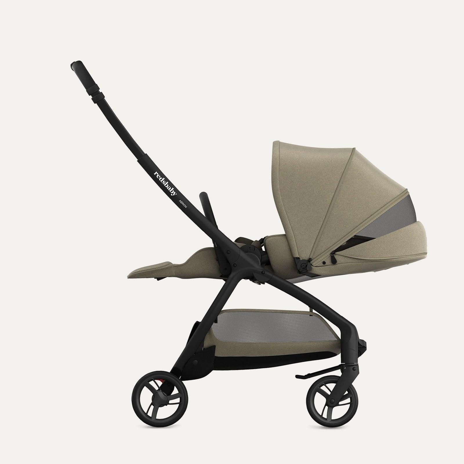 Side view of the taupe-colored Redsbaby Aeron stroller with a black frame in a fully reclined position, suitable for a newborn. The stroller features a large, extendable canopy with a mesh window, an adjustable footrest, and a spacious storage basket underneath. The sleek design emphasizes comfort and practicality. Side view of the taupe-colored Redsbaby Aeron stroller with a black frame in a fully reclined position, suitable for a newborn. The stroller features a large, extendable canopy with a mesh window, an adjustable footrest, and a spacious storage basket underneath. The sleek design emphasizes comfort and practicality.