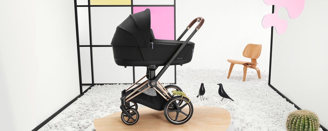 A sophisticated CYBEX Priam 4 stroller with a rosegold chassis and deep black carrycot stands prominently in a modern room with artistic decor, blending functionality with high-end design.
