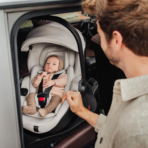 Father adjusting the harness of the Britax Römer Baby-Safe Pro Lux Infant Car Seat in Taupe, with his newborn safely secured inside, showing the car seat’s ease of use and comfort.