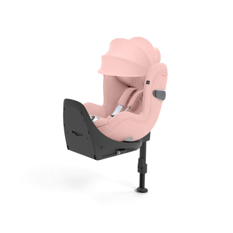 CYBEX Sirona T i-Size Plus in Peach Pink with a protective sun canopy, featuring a soft pink fabric, advanced safety harness, and sturdy adjustable base with a leg support for enhanced stability.